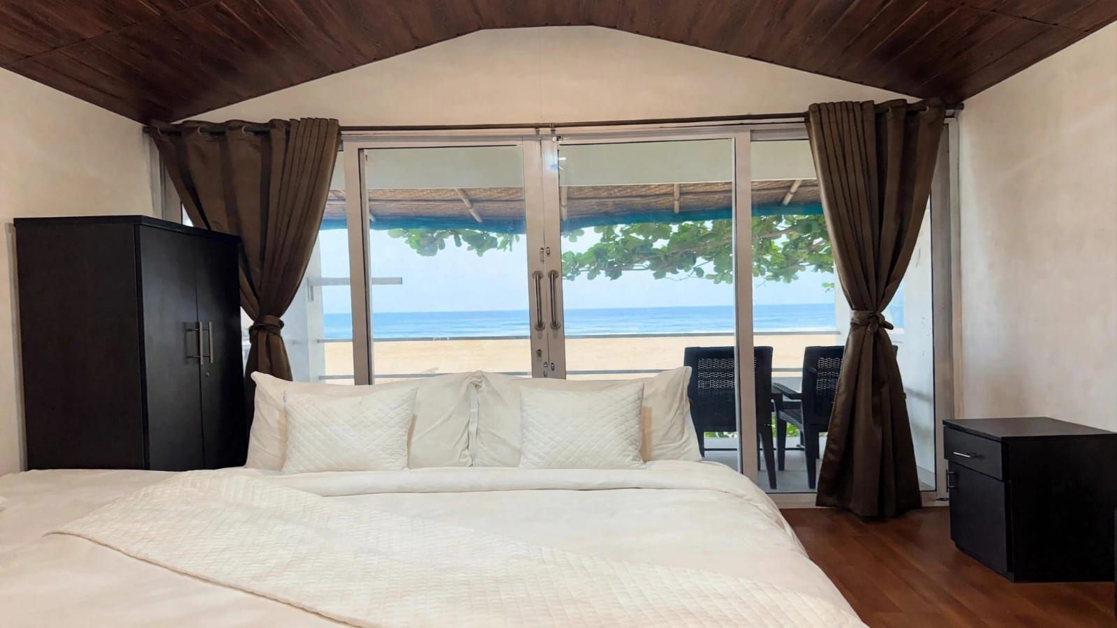 Un dormitorio con una cama grande, un armario y vista a la playa a través de una puerta corredera.