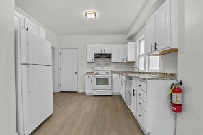 A kitchen with white cabinets, a stove, and a microwave. - Cozy 3BR Detroit Home | Sleeps 8 | Self Check-in (Detroit)