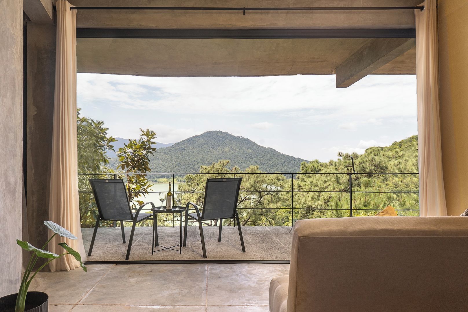 A balcony with two chairs and a table, overlooking a mountainous landscape.