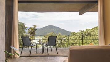 A balcony with two chairs and a table, overlooking a mountainous landscape.