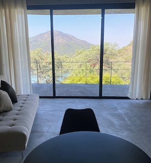 A modern living room with a large window, a sofa, and a round table. - Modern Loft - Spectacular Mountain and Lake Views (Valle de Bravo)