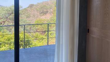Una habitación con un amplio ventanal corredera que da a un balcón con baranda de metal.