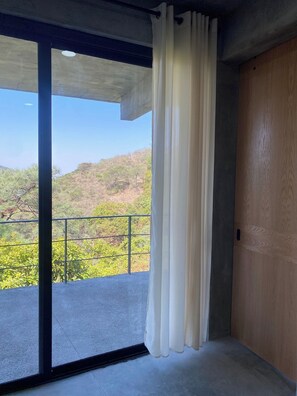 Una habitación con un amplio ventanal corredera que da a un balcón con baranda de metal.