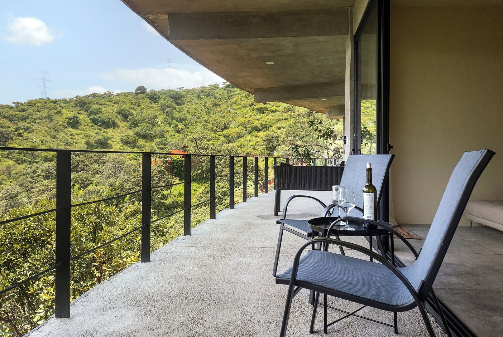 A balcony with a table and chairs, overlooking a lush green landscape.