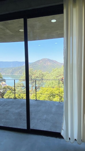 A room with a large window offering a view of a mountainous landscape and a body of water. - Modern Loft - Spectacular Mountain and Lake Views (Valle de Bravo)