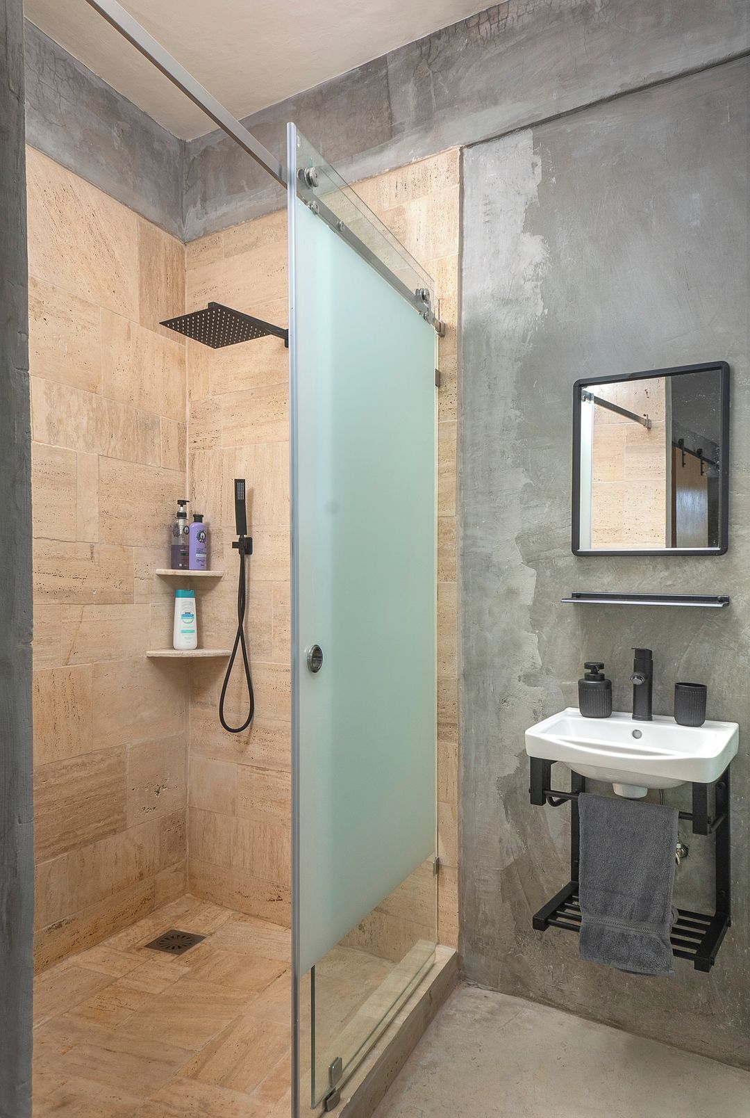 Un bagno moderno con box doccia in vetro, un lavandino bianco e uno specchio sopra.
