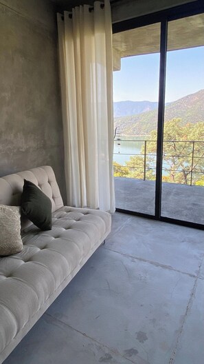 Una habitación con sofá, vistas a un lago y un paisaje montañoso.
