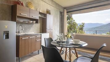 A modern kitchen with a built-in refrigerator, wooden cabinets, and a dining area with a glass table and chairs.