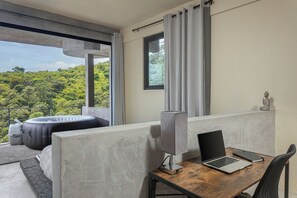 Ein modernes Zimmer mit Balkon, ein Laptop auf einem Holztisch und eine Couch.