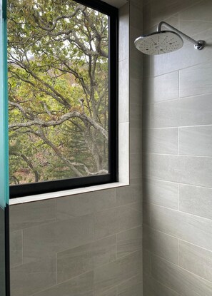 A shower with a curved head, a window with a black frame, and grey tiled walls. - Spectacular Bosque Condo – Lake View – Jacuzzi (Valle de Bravo)
