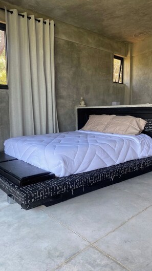 A bed with a quilted white duvet, a black headboard, and a bench at the foot of the bed. - Spectacular Bosque Condo – Lake View – Jacuzzi (Valle de Bravo)