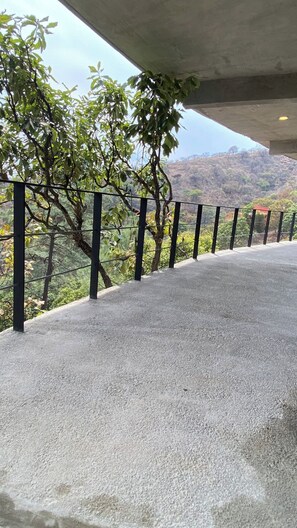A concrete ledge with a metal railing overlooking a hilly landscape. - Spectacular Bosque Condo – Lake View – Jacuzzi (Valle de Bravo)