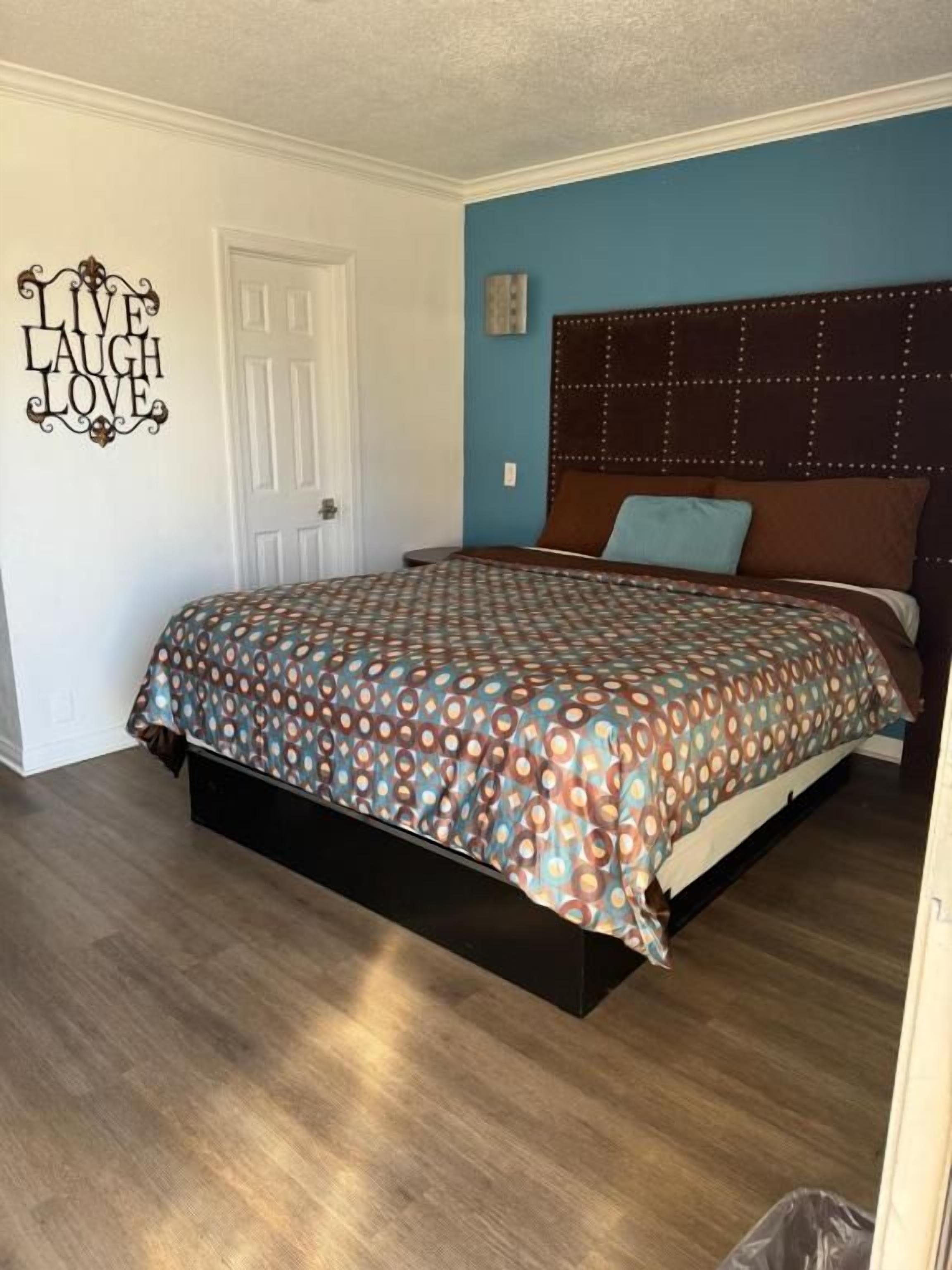 Quarto com cama, cabeceira e um objeto decorativo na parede.