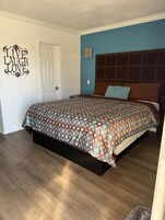 Quarto com cama, cabeceira e um objeto decorativo na parede.