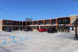 Un motel con varias habitaciones, un estacionamiento y algunos coches aparcados.