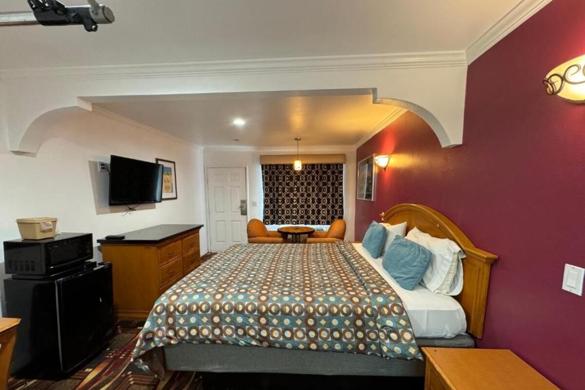 Een hotelkamer met een bed, een bureau, een televisie en een behang met patroon.