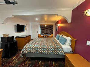 Een hotelkamer met een bed, een bureau, een televisie en een behang met patroon.