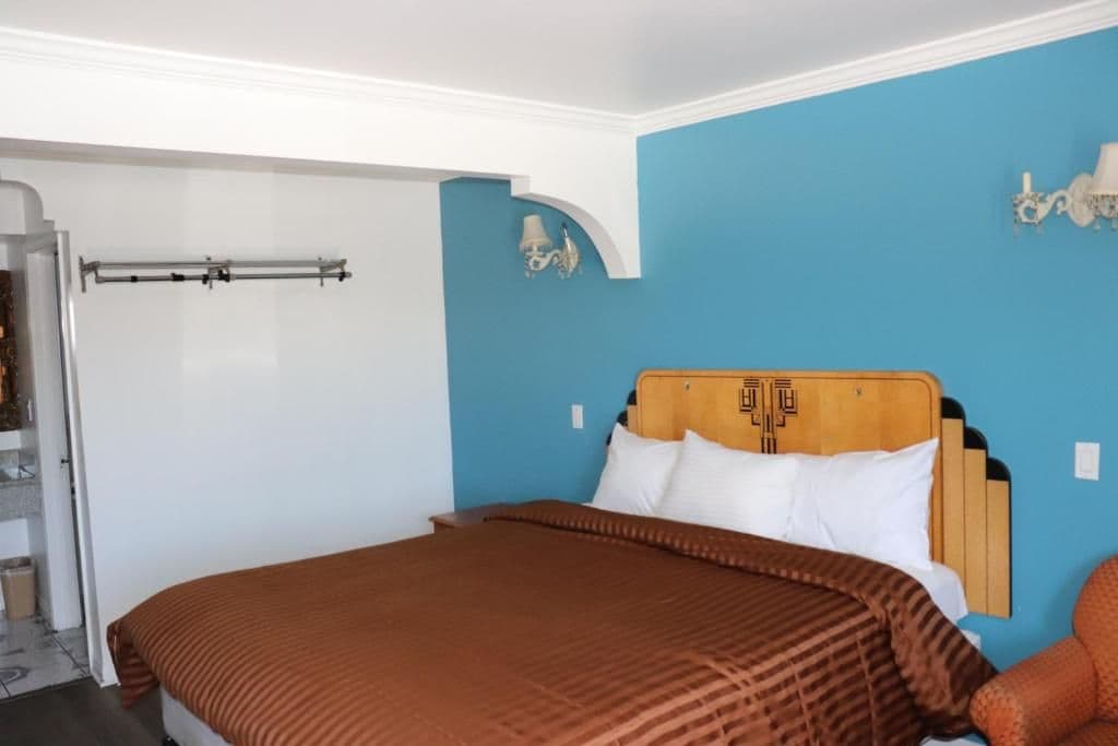 A bedroom with a bed, a wooden headboard, and a blue wall.