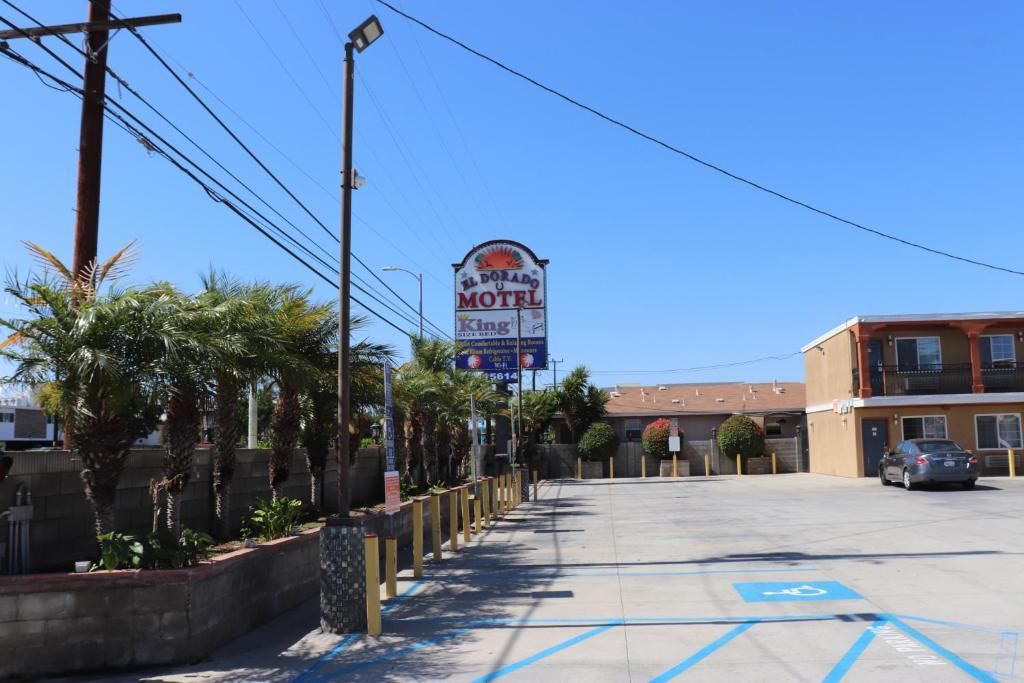 Um motel sob um céu azul límpido, com estacionamento incluindo vagas para deficientes e a placa indicativa do motel.