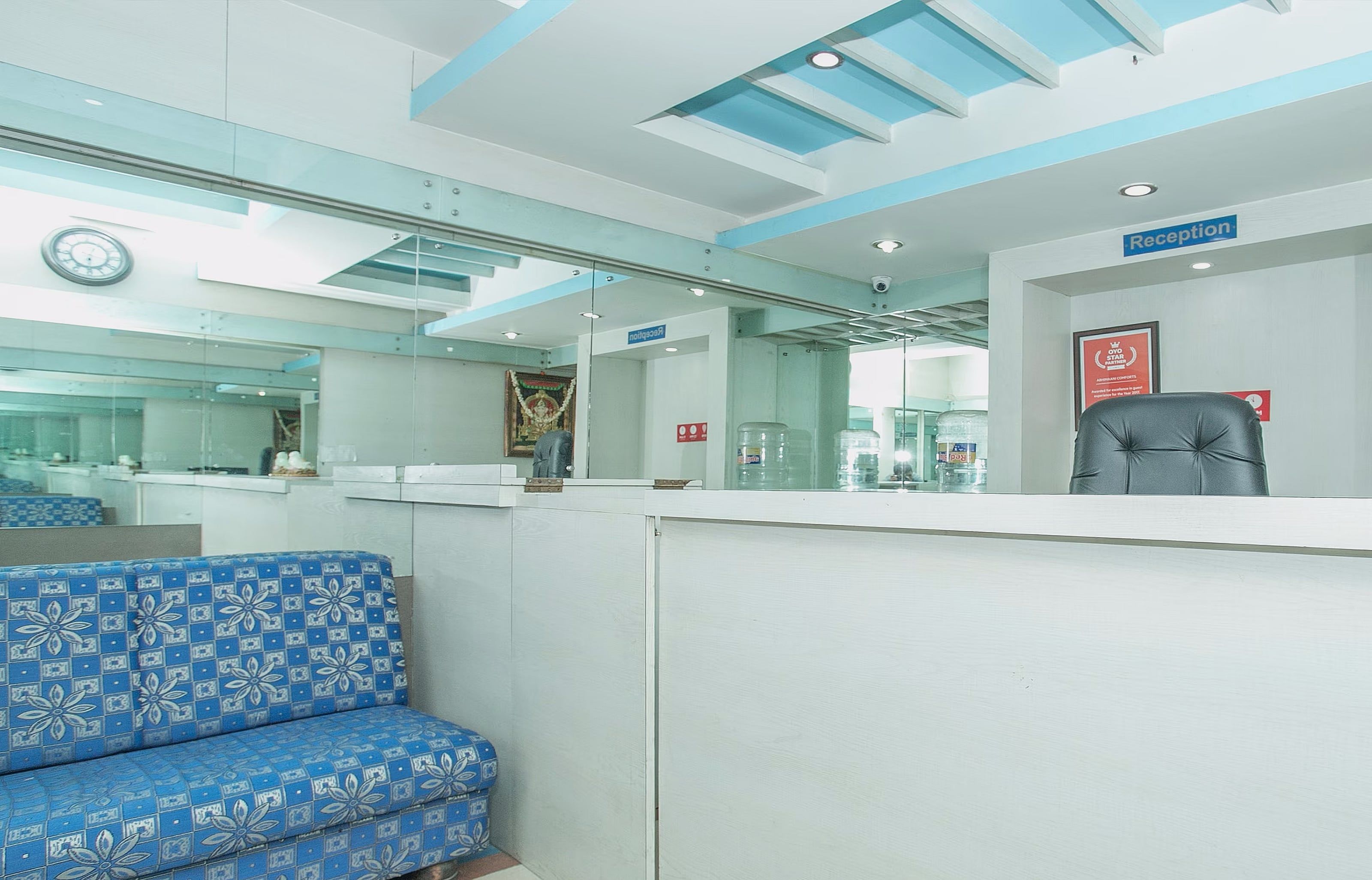 A reception area with a reception desk, a blue patterned sofa, and a clock on the wall.