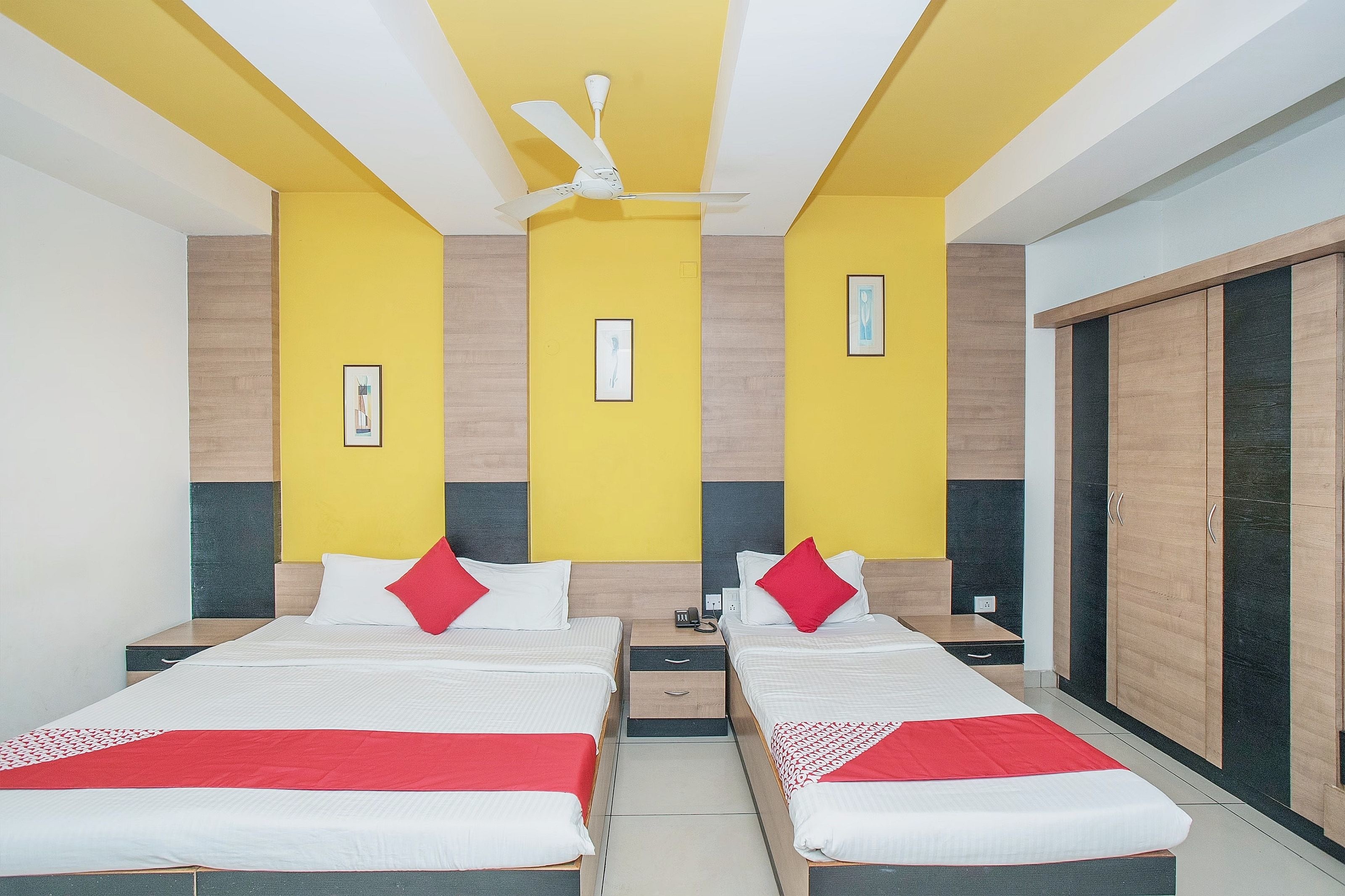 Habitación de hotel con dos camas, un ventilador de techo y un armario.