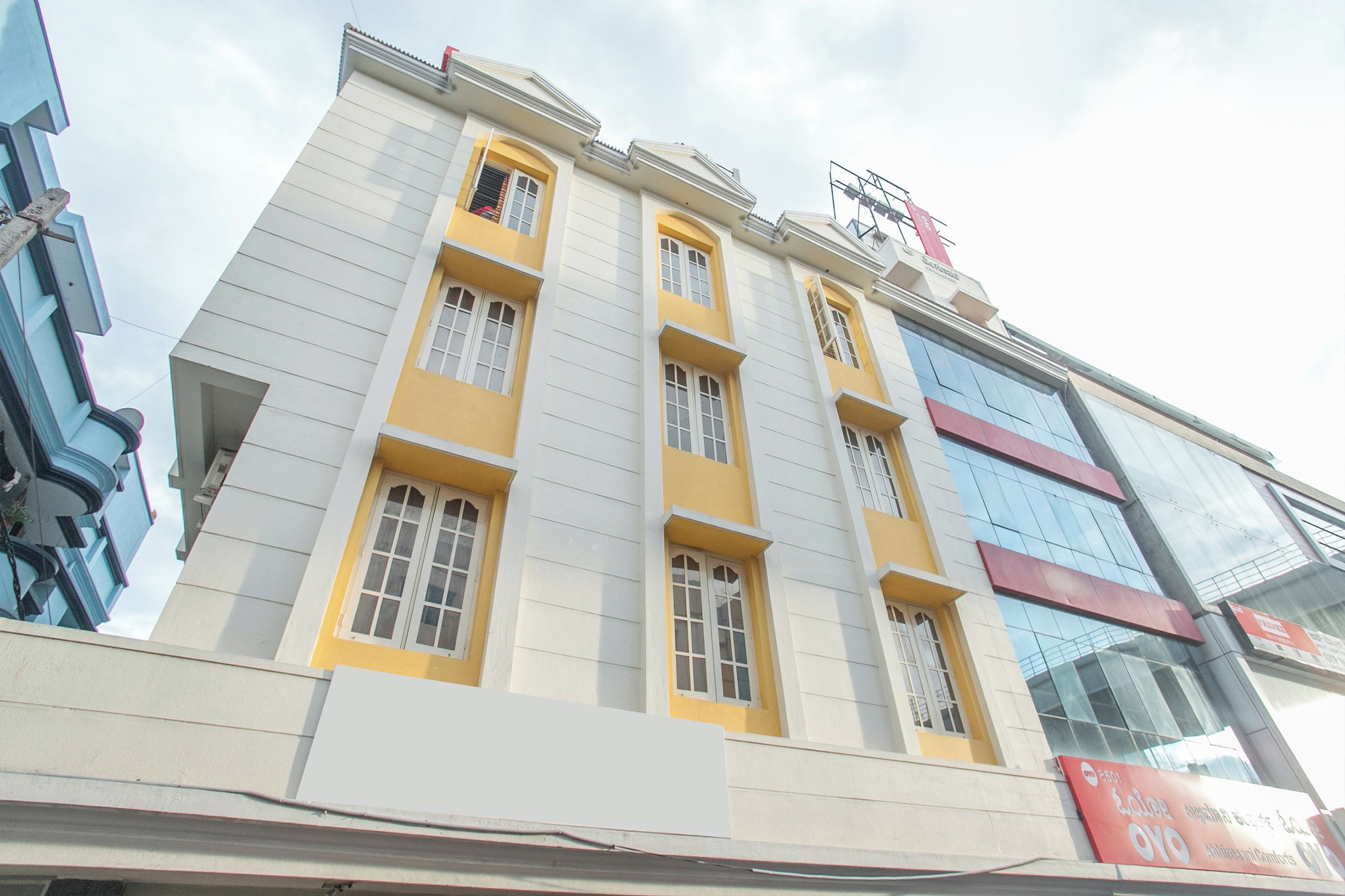 A multi-story building with a yellow and white facade, large windows, and a sign indicating it is a hotel.