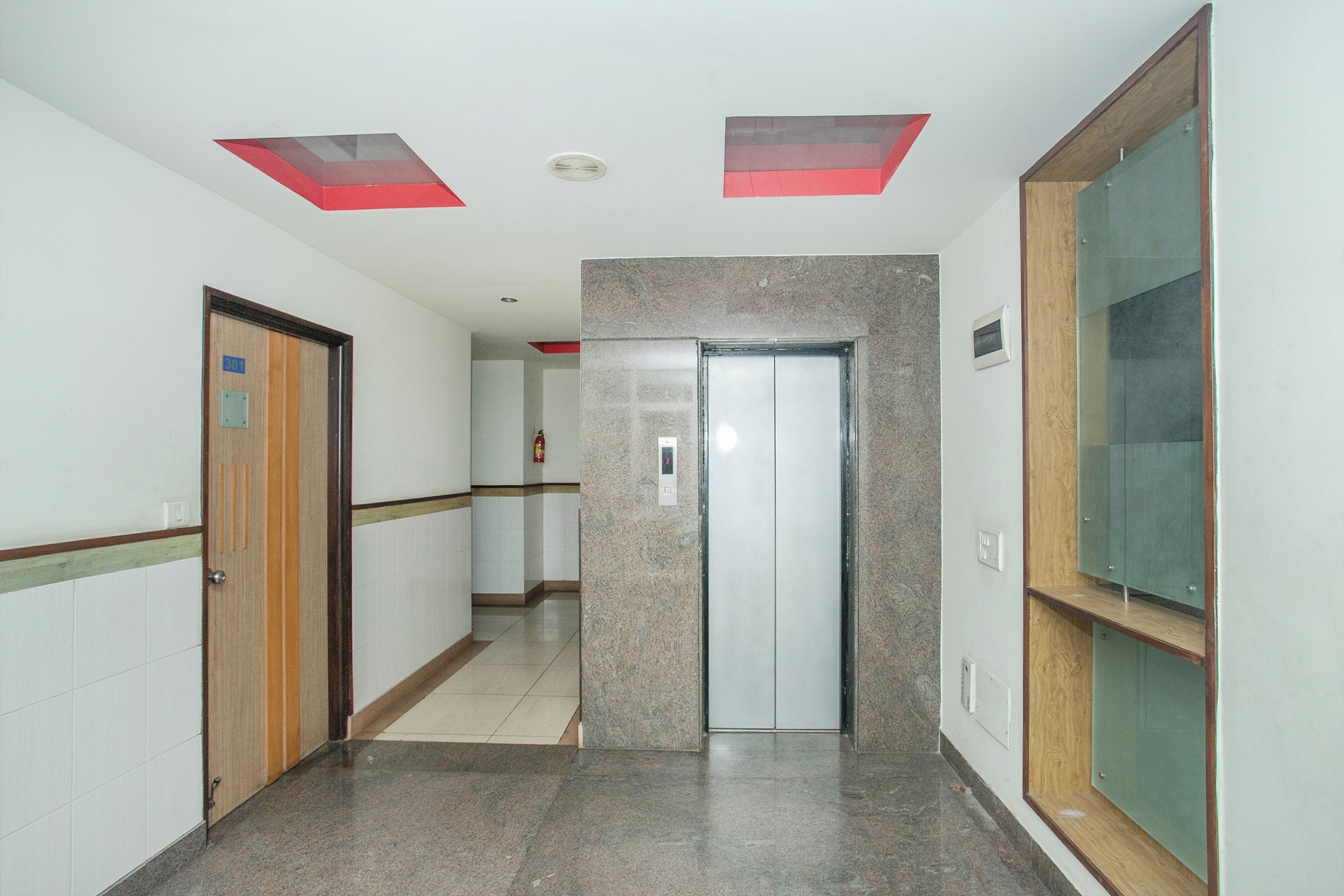 Un pasillo con una puerta marcada '301', un extintor y un interfono instalado en la pared.