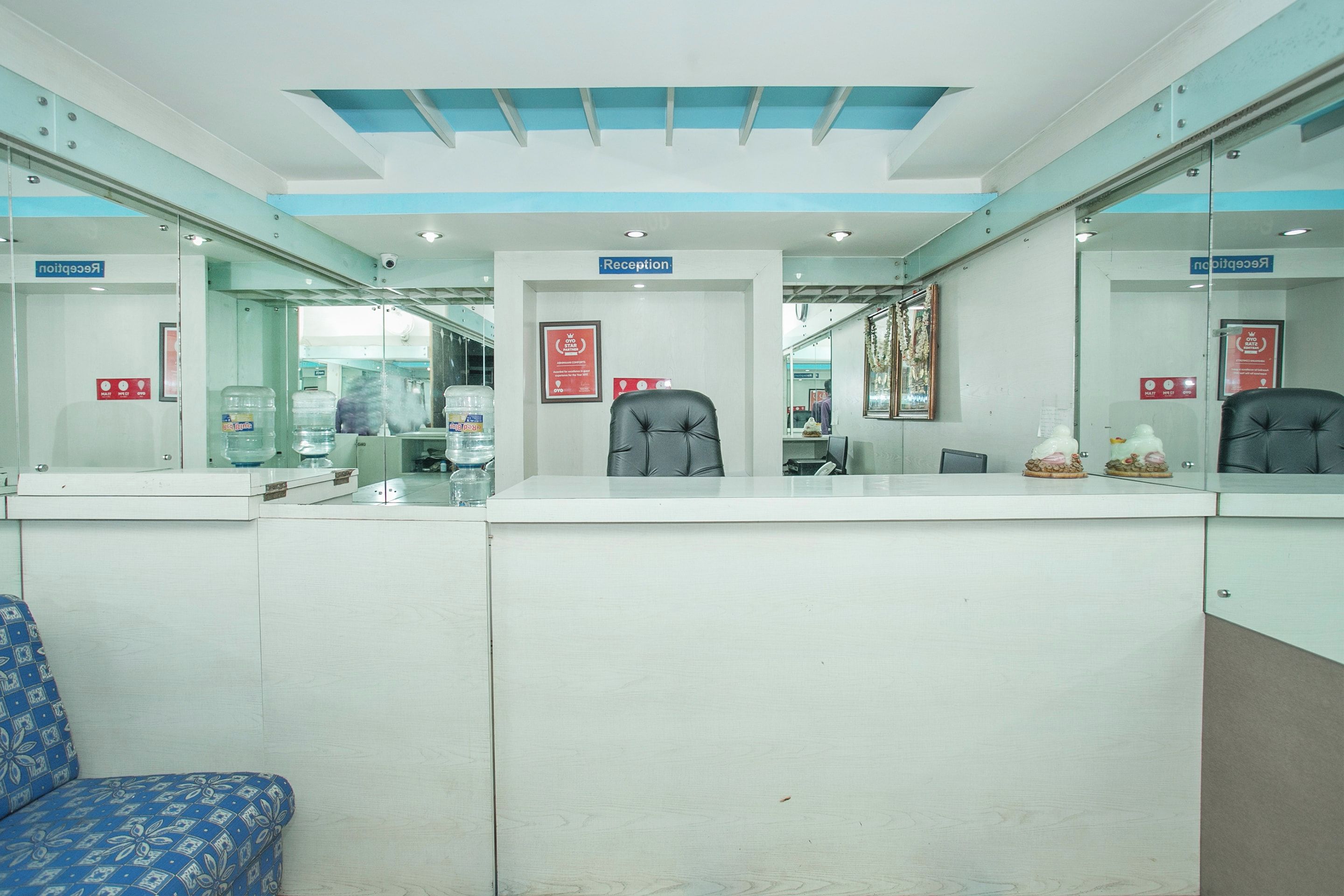 A reception area with a reception desk, chairs, and a blue patterned sofa.
