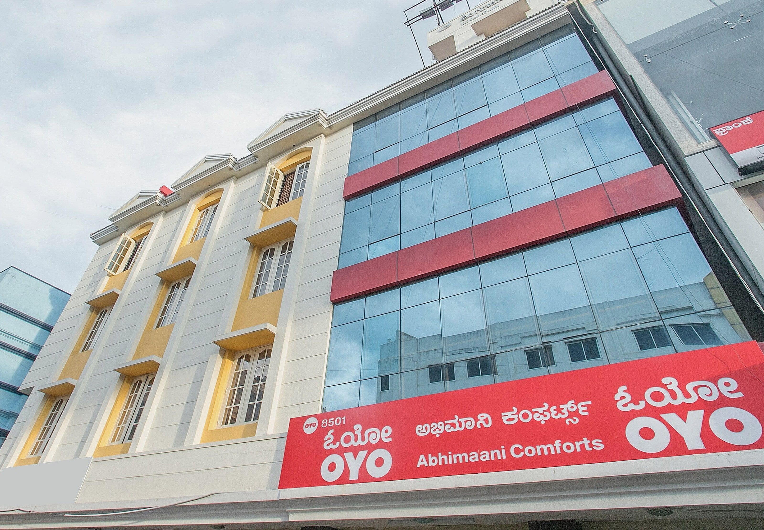 Um edifício com placa vermelha e branca para Abhimaani Comforts.