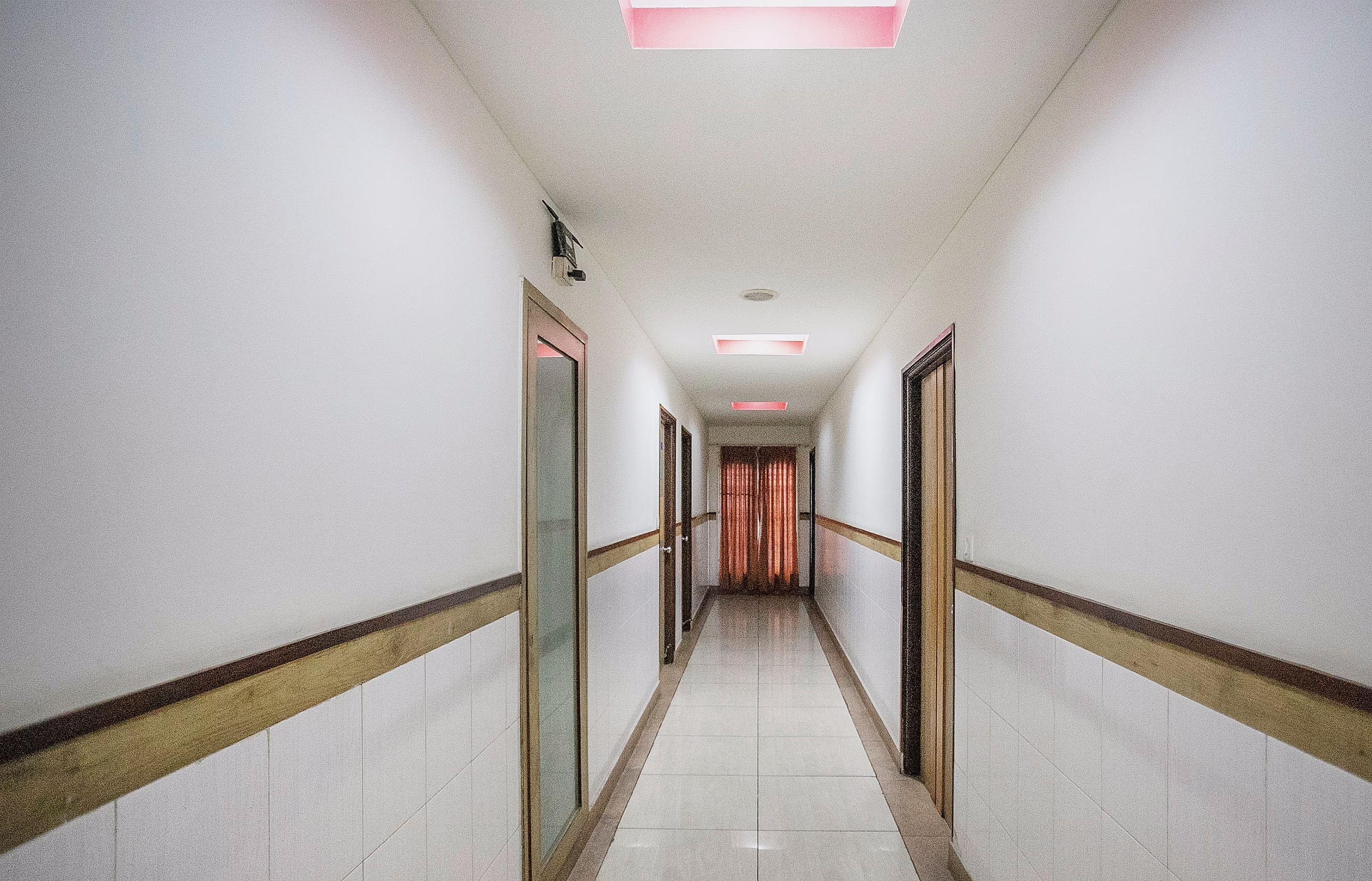 A long, narrow hallway with doors on both sides, leading to a room at the end.