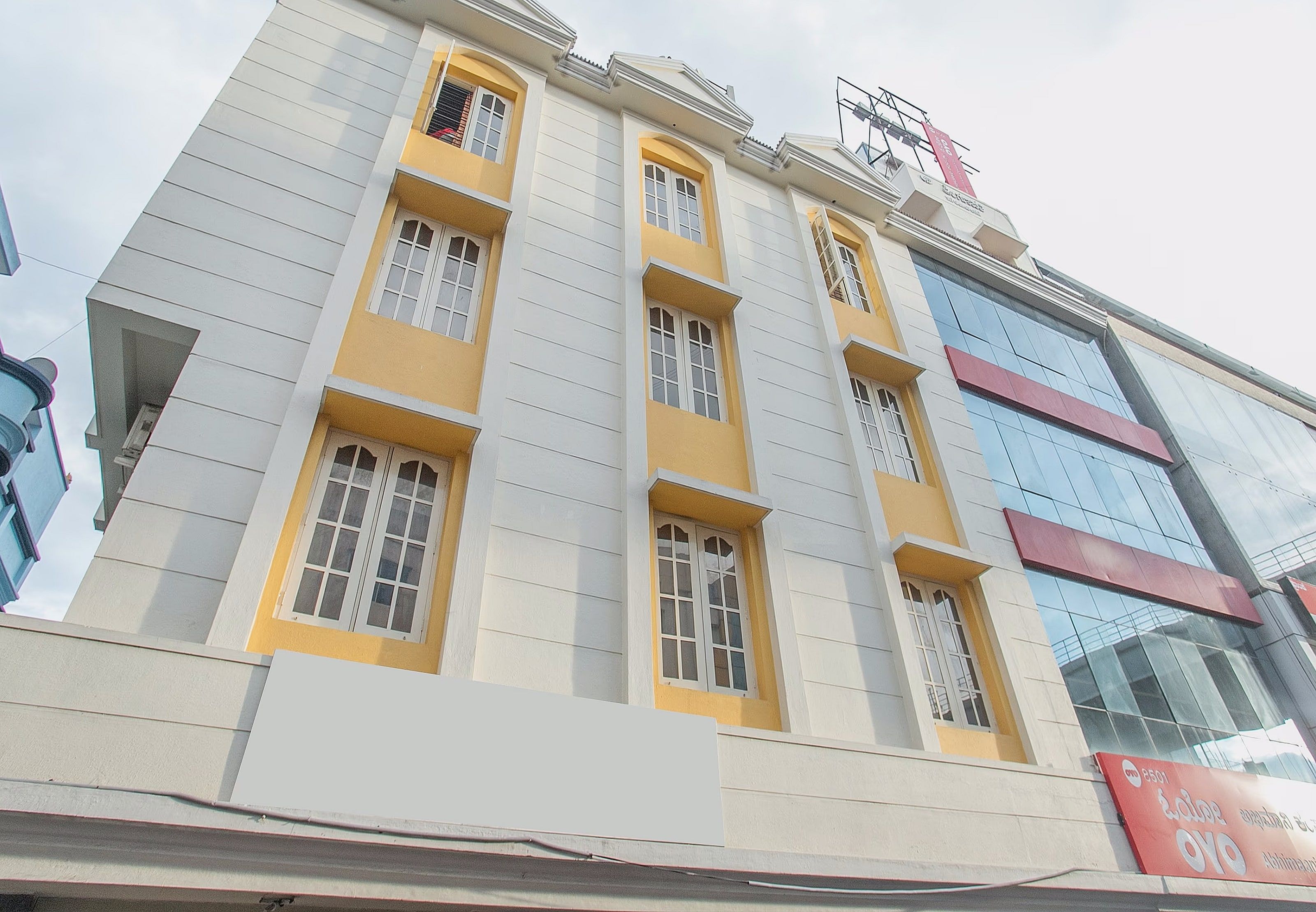 A multi-story building with a yellow facade, large windows, and a sign with a logo.