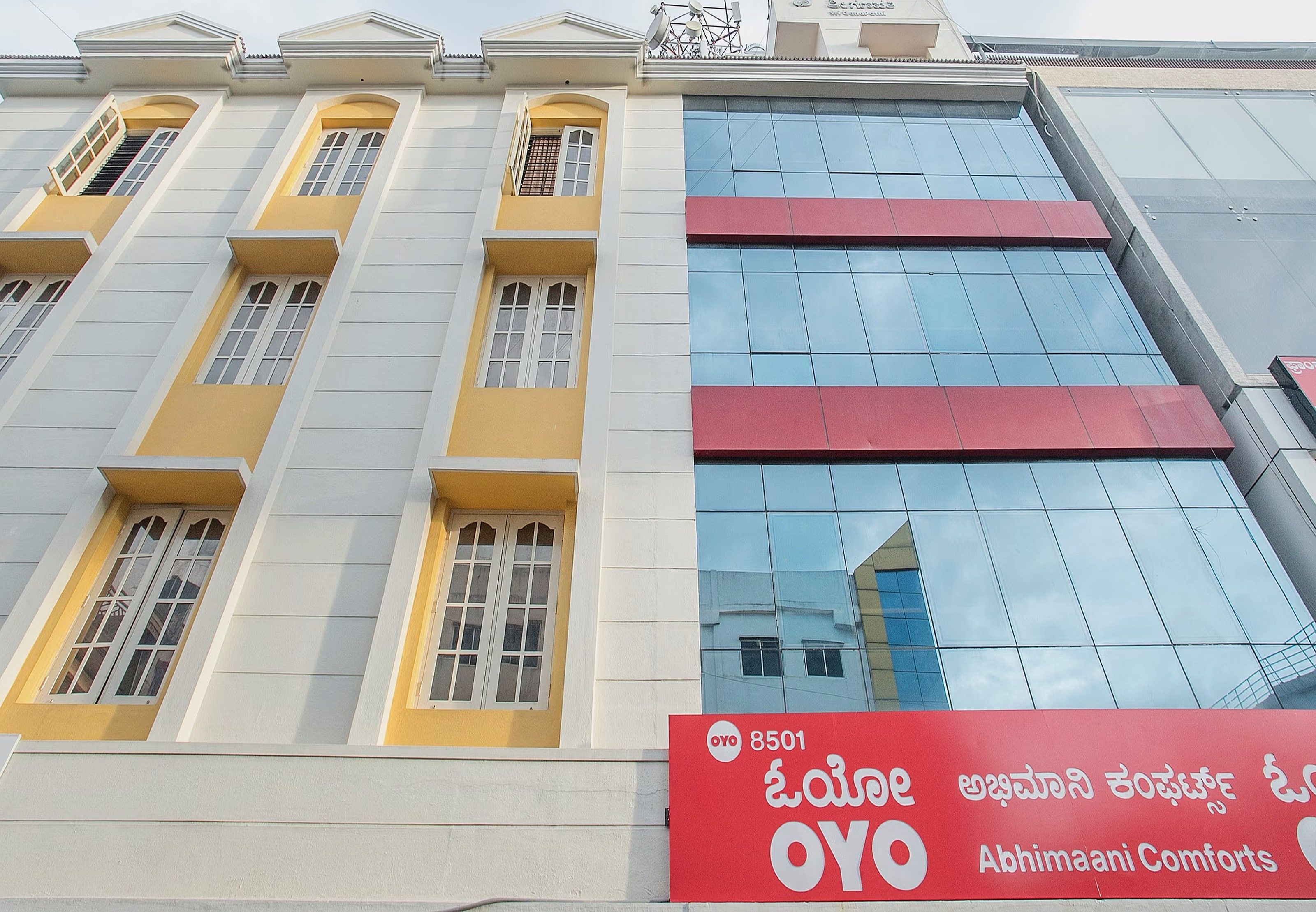 A building with multiple windows and a red sign for OYO Abhimaani Comforts.