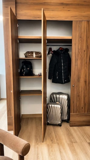 A wooden wardrobe with open doors revealing shelves, a hanging jacket, and two suitcases. - Condesa Residence - Roma Luxury Suite 405 (Ciudad de México)