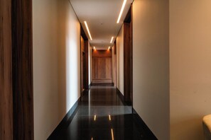 A long, narrow hallway with a glossy floor, wooden paneling on the walls, and recessed lighting. - Condesa Residence - Roma Luxury Suite 405 (Ciudad de México)