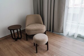A room with a beige armchair, a round ottoman, and a small round table. - Condesa Residence - Roma Luxury Suite 407 (Ciudad de México)