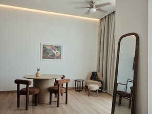 A modern room with a round table, two chairs, a small stool, a sofa, a mirror, a ceiling fan, and a framed picture on the wall. - Condesa Residence - Roma Luxury Suite 407 (Ciudad de México)