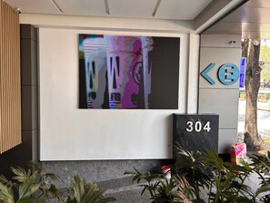 A modern building entrance with a digital display, a sign with the number 304, and a directional sign. - Condesa Residence - Roma Luxury Suite 406 (Ciudad de México)