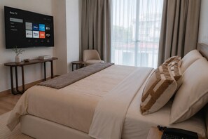 A hotel room with a bed, a TV mounted on the wall displaying streaming services, a small table with a vase, and a chair. - Condesa Residence - Roma Luxury Suite 406 (Ciudad de México)