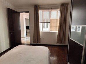 A hotel room with a bed, a window with curtains, a door, and a view of the hallway. - Condesa Residence Campeche 5 (Ciudad de México)