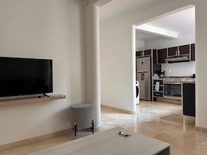 Ein modernes Wohnzimmer mit einem Flachbildfernseher, einem kleinen Hocker und einem Couchtisch.