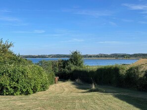A grassy pathway leading to a body of water with a clear sky above. - Summer house with views over Lammefjorden (Grevinge)