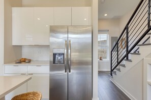 A modern kitchen with a stainless steel refrigerator, white cabinetry, and a black staircase. - 4 Modern Townhomes | Balconies | Walk to Cafés + Shops | Lischey Full Buyout (Nashville)