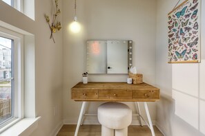 A wooden vanity with a mirror, a stool, and a wall-mounted light fixture. - 4 Modern Townhomes | Balconies | Walk to Cafés + Shops | Lischey Full Buyout (Nashville)