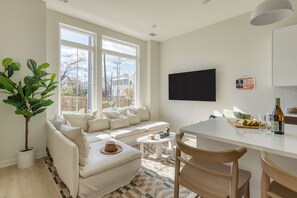 A modern living room with a white sofa, a coffee table, and a dining area with a white table and chairs. - 4 Modern Townhomes | Balconies | Walk to Cafés + Shops | Lischey Full Buyout (Nashville)