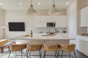 A modern kitchen with white cabinetry, a central island with bar stools, and pendant lighting. - 4 Modern Townhomes | Balconies | Walk to Cafés + Shops | Lischey Full Buyout (Nashville)