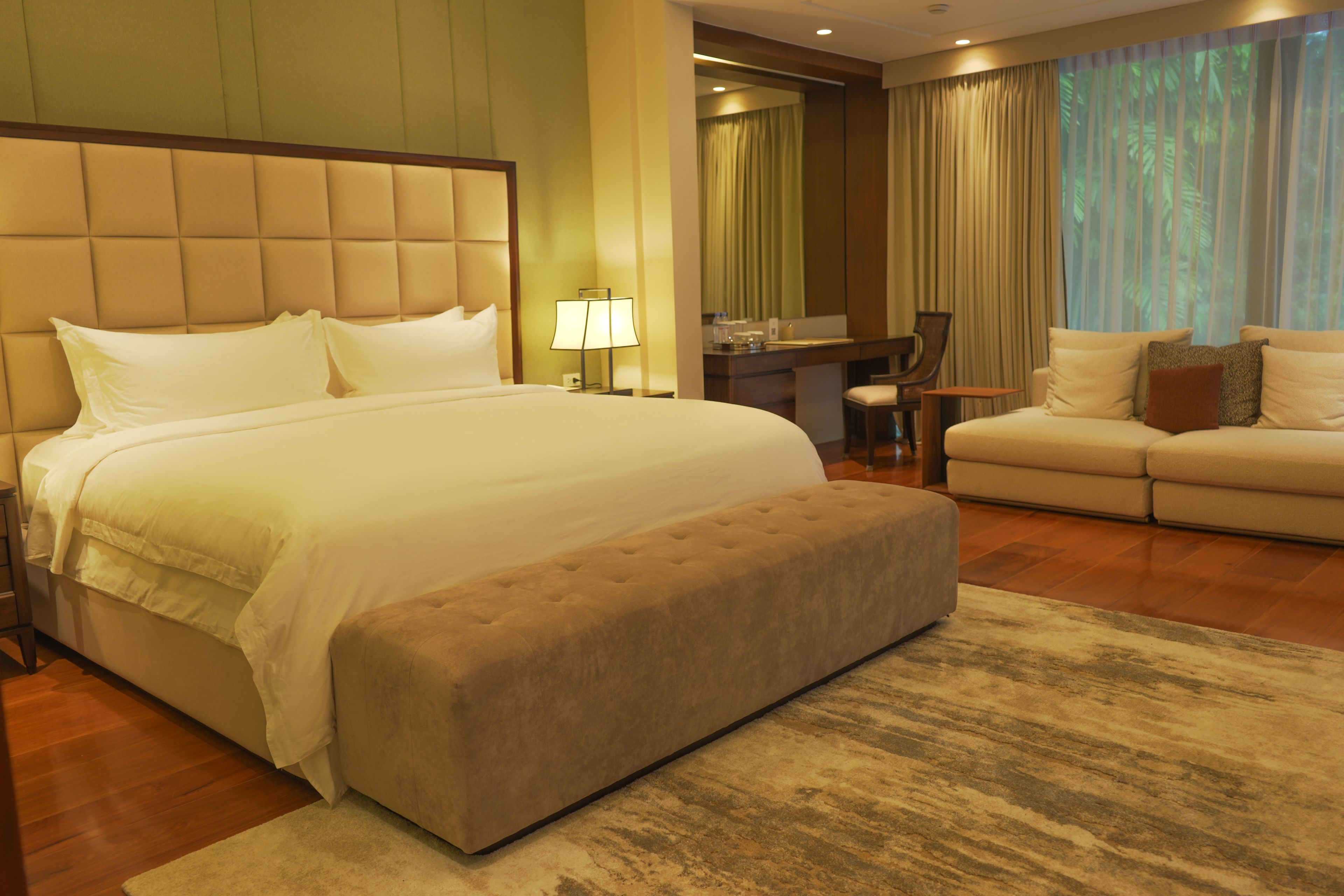 A hotel room with a large bed, a sofa, a desk, and a chair.