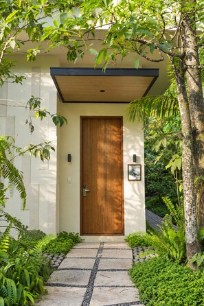 A modern house with a wooden door, a small porch, and a stone pathway leading to the entrance.