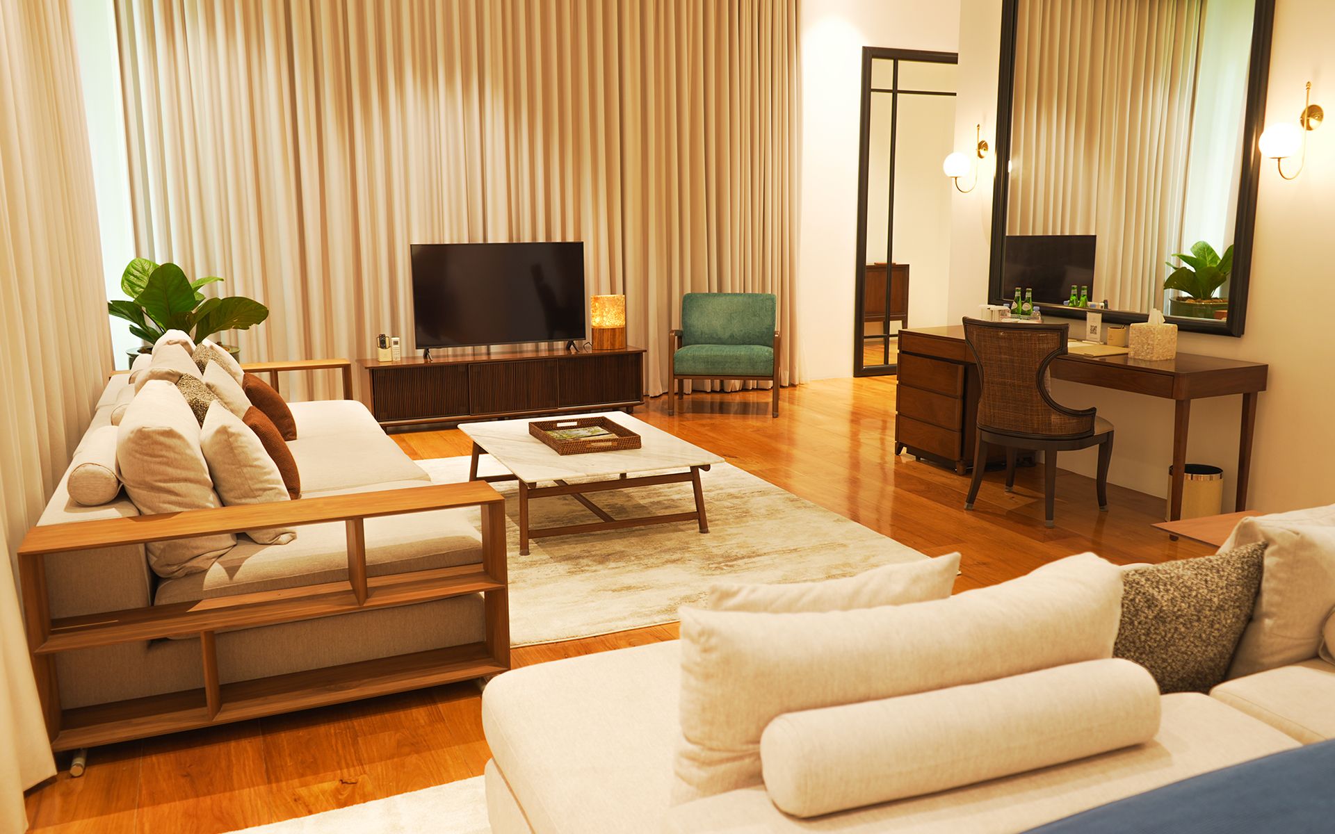 A modern living room with a sofa, a coffee table, a TV, a desk, and a chair.
