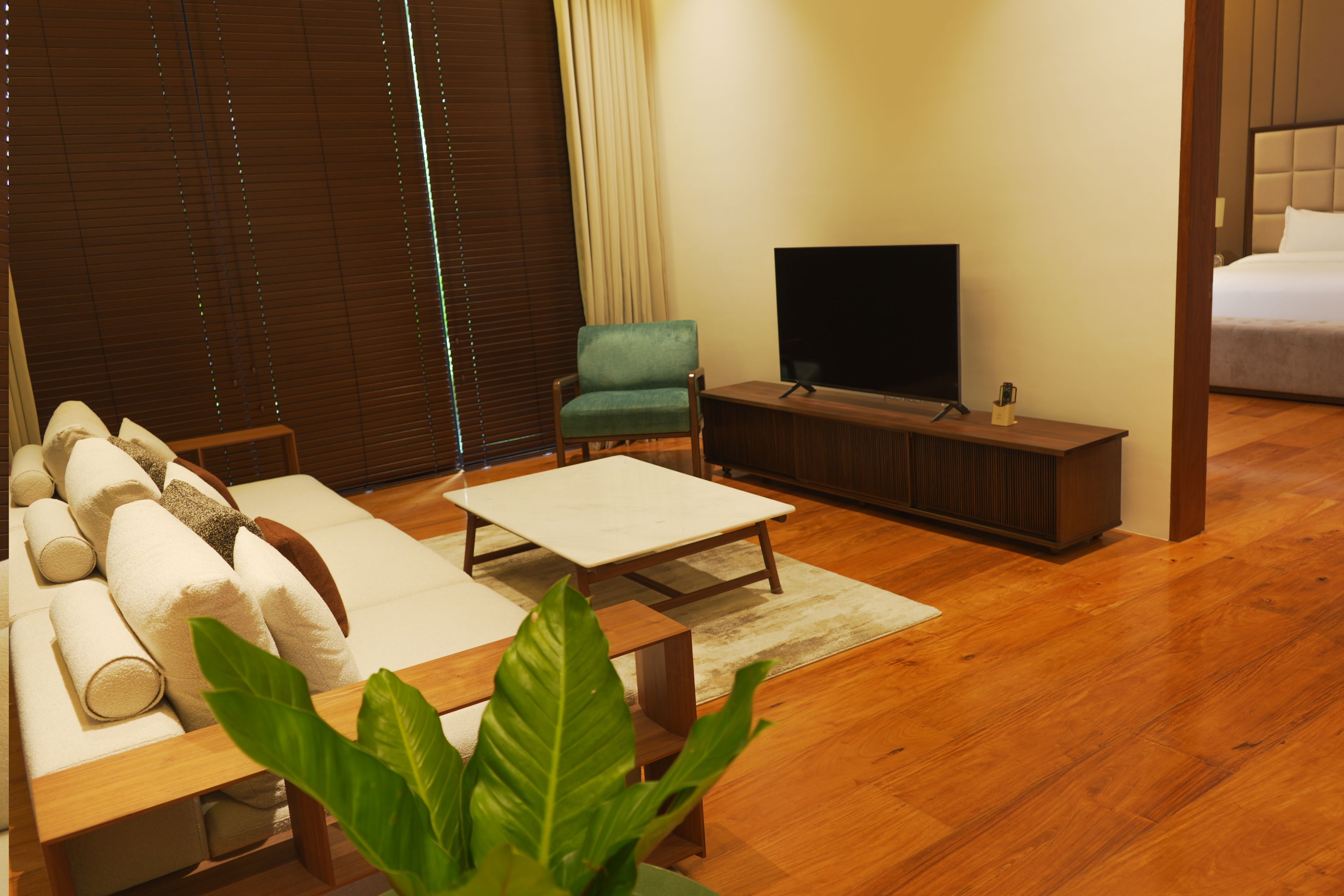 Una sala moderna con un sofá, una mesa de centro, un televisor y un sillón verde.