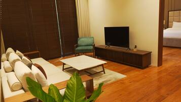 Una sala moderna con un sofá, una mesa de centro, un televisor y un sillón verde.